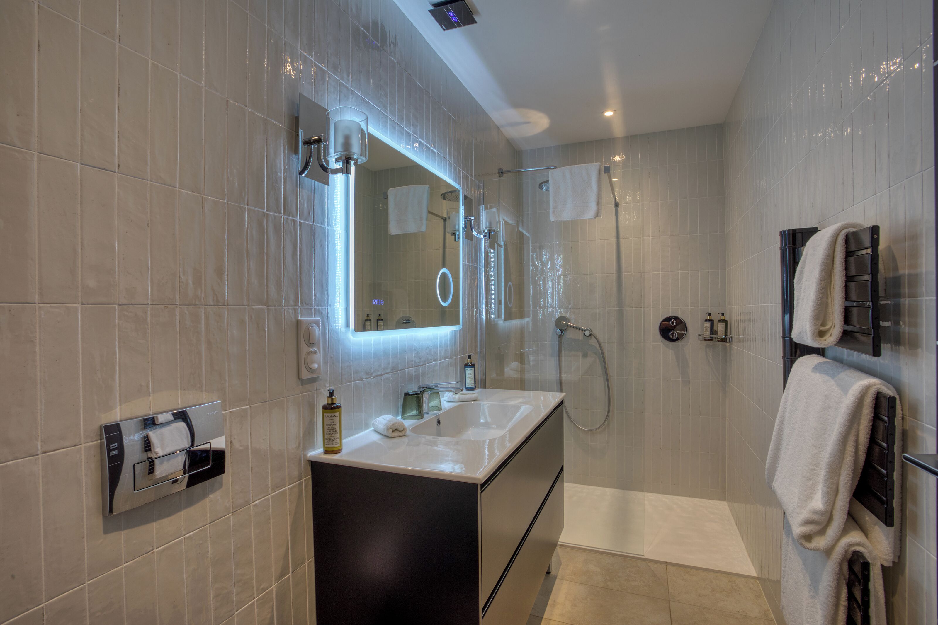 Un baño moderno con un espejo grande, un lavamanos, una ducha y un perchero para toallas.