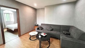 Una sala moderna con un sofá gris, dos mesas redondas de centro y suelo de madera.