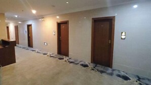 Un pasillo de hotel con varias puertas, piso alfombrado e iluminación empotrada.