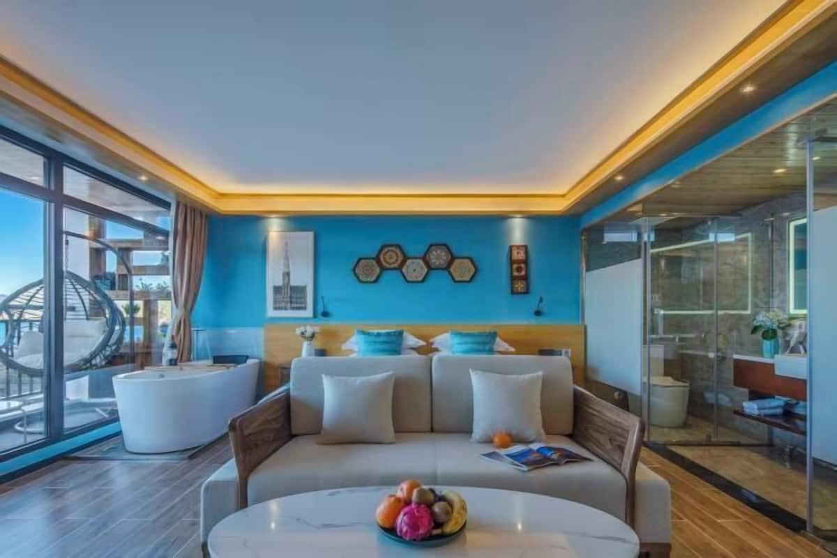 A modern living room with a blue accent wall, a round coffee table with fruit, and a sofa with cushions.