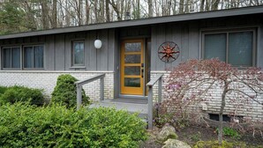 Ein modernes Haus mit gelber Tür, einer kleinen Veranda und einer Sonnendekoration an der Wand.