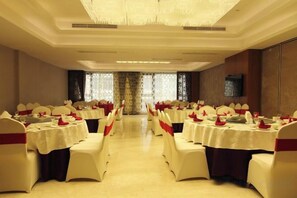 A banquet hall with multiple round tables, each with a white tablecloth and red napkins. - Royal Garden Hotel (Yueqing)