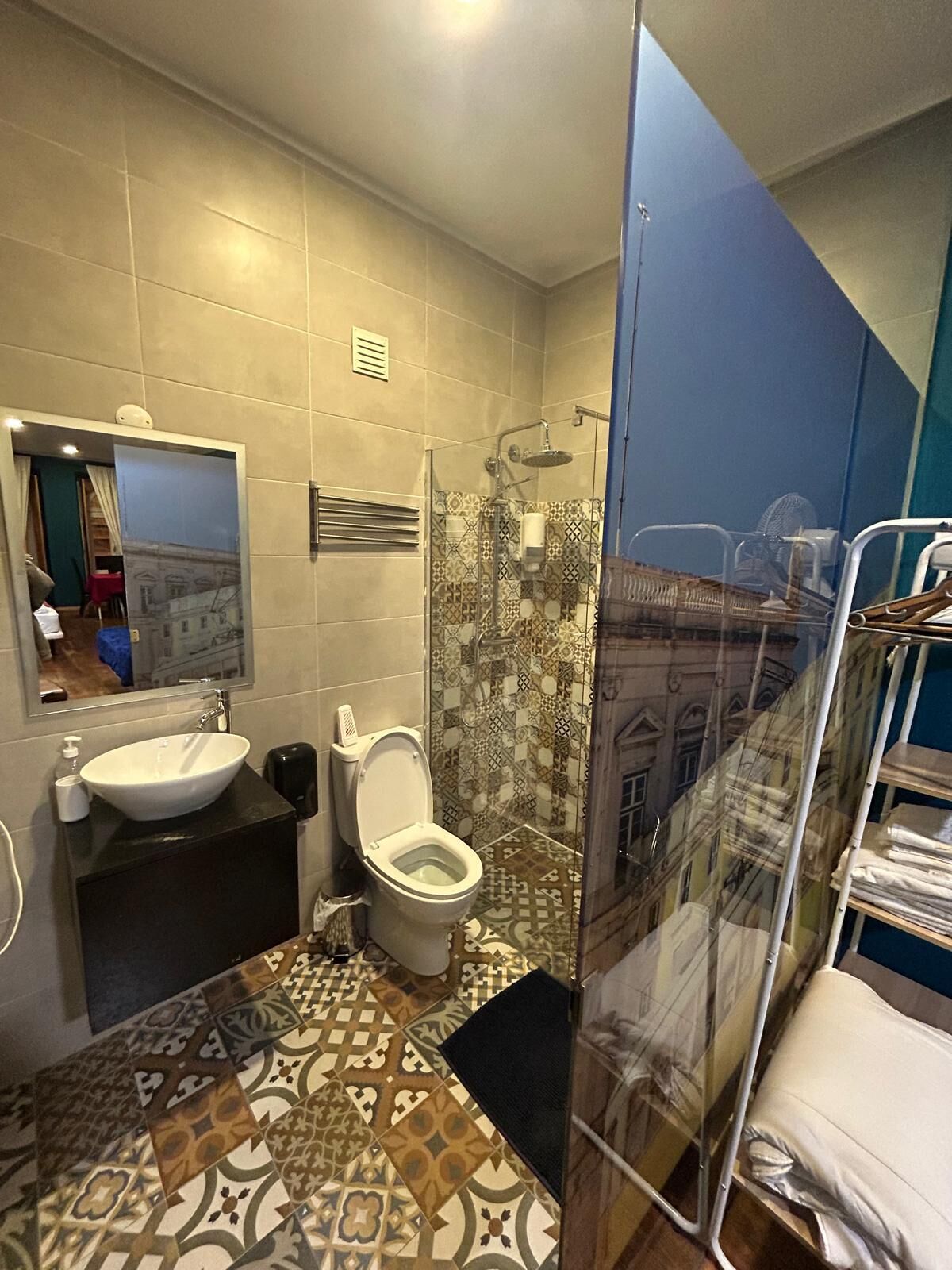 A bathroom with a large mirror, a sink, a toilet, and a shower area.