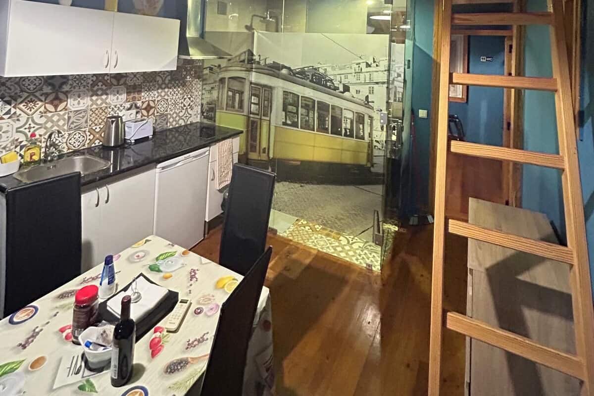 A kitchen with a dining table set, a staircase leading to an upper level, and a view of a tram outside.
