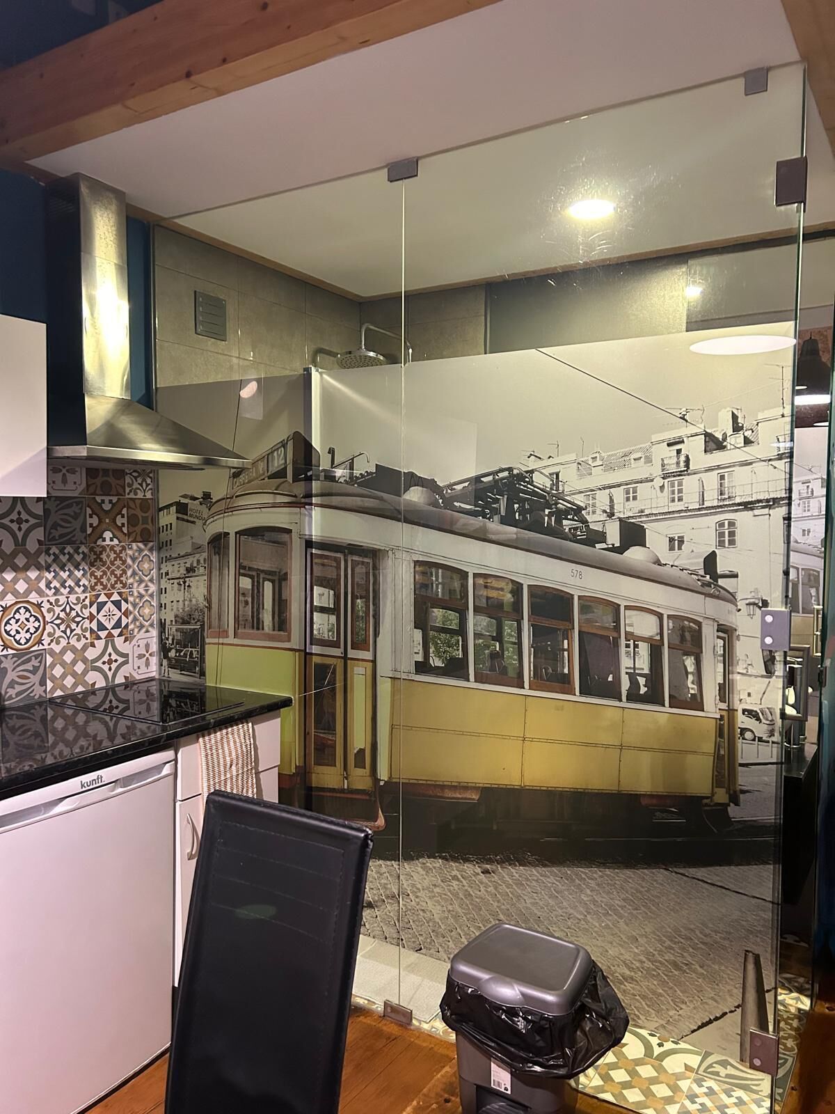 A kitchen with a glass partition reflecting a tram.