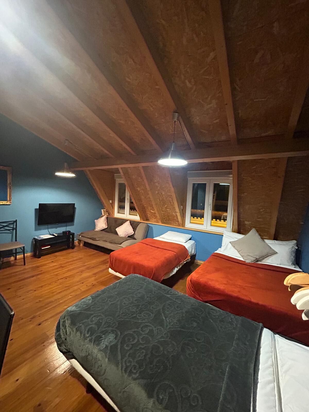 Ein Zimmer mit zwei Betten, einem Fernseher, einem Schreibtisch und einem Fenster.