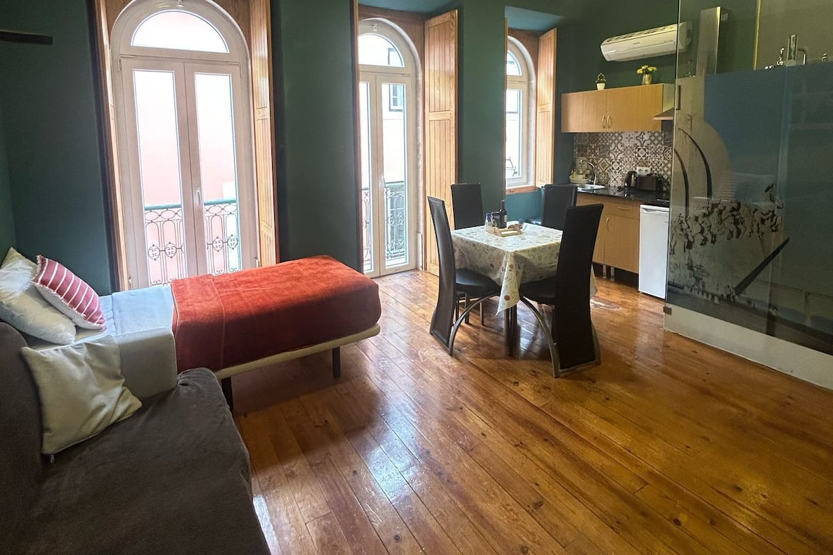 A cozy room with a bed, a dining table, and a kitchenette.