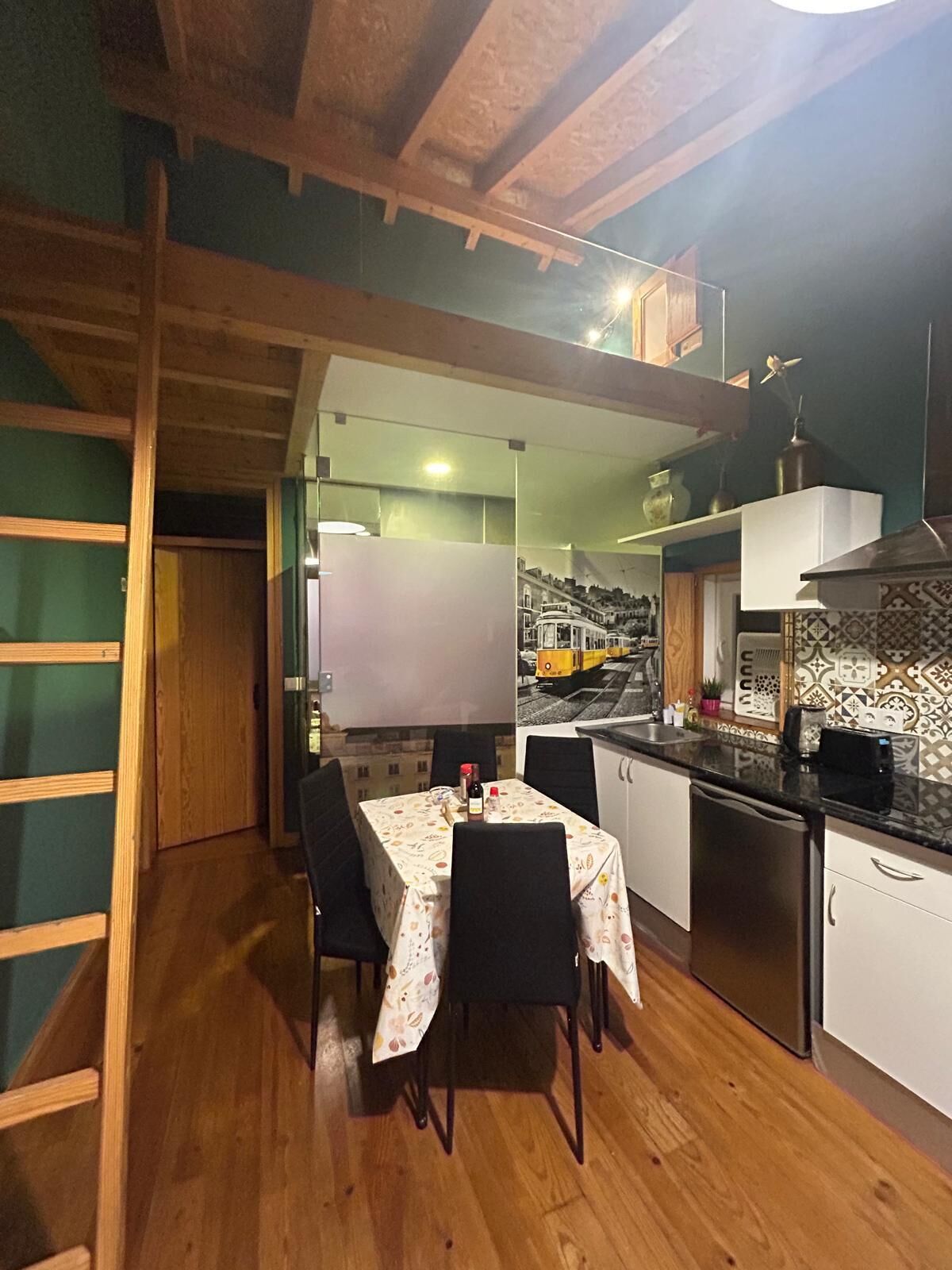Una cucina compatta con travi in legno, un tavolo da pranzo con sedie e un’isola con lavandino.