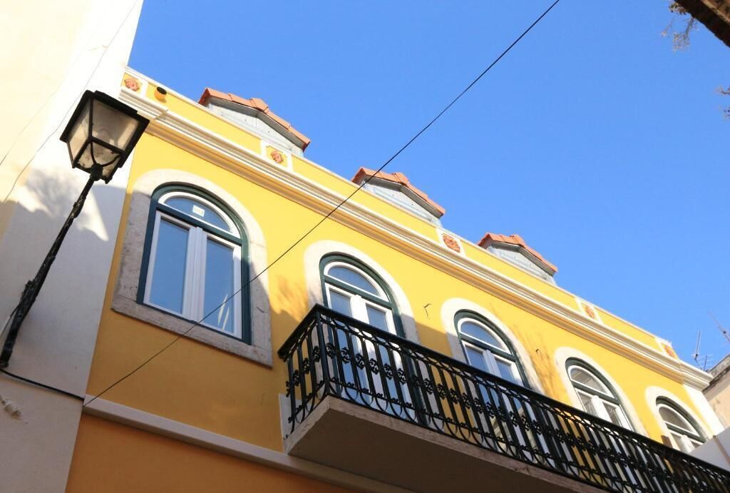 A yellow building with arched windows and a balcony with black railings.