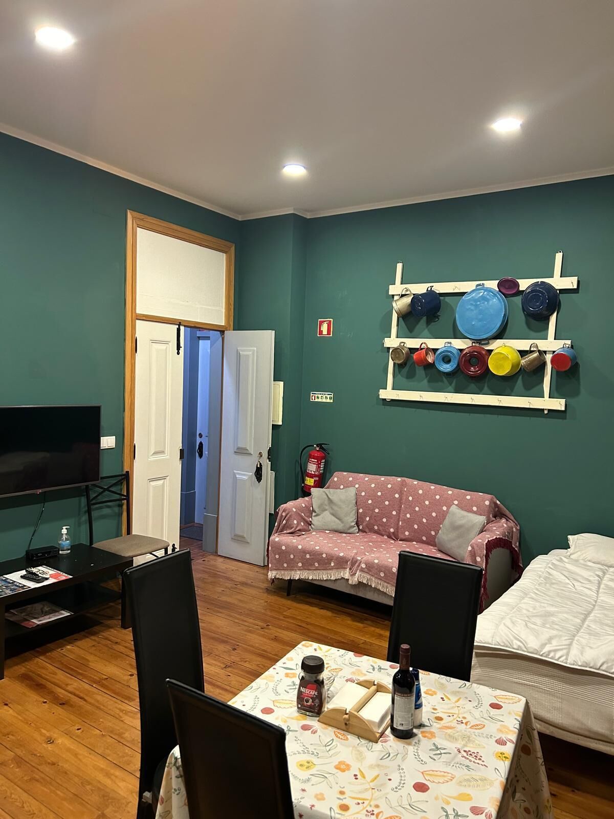 Une pièce confortable équipée d’un téléviseur, d’un canapé, d’une table à manger et d’un porte-ustensiles fixé au mur.