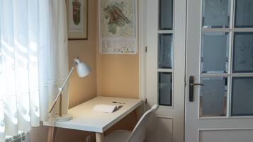 Een studeerkamer met een bureau, stoel, lamp en een kaart aan de muur.