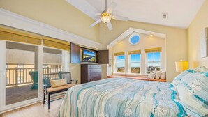 Un dormitorio con cama, ventilador de techo, televisor y ventana con vistas.