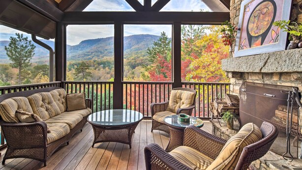 Eine überdachte Terrasse mit Korbmöbeln, einem Kamin und Blick auf die Berge.