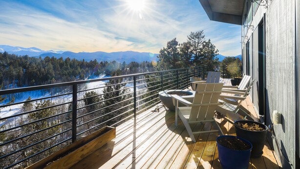A wooden deck with outdoor seating, a fire pit, and a view of a snowy landscape with mountains. - Sunrise+Sunset views - HotTub / Firepit / RecRoom / BBQ / Yoga studio /Treadmill (Central City)