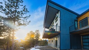 A modern two-story building with a balcony, surrounded by trees and a clear sky. - Sunrise+Sunset views - HotTub / Firepit / RecRoom / BBQ / Yoga studio /Treadmill (Central City)
