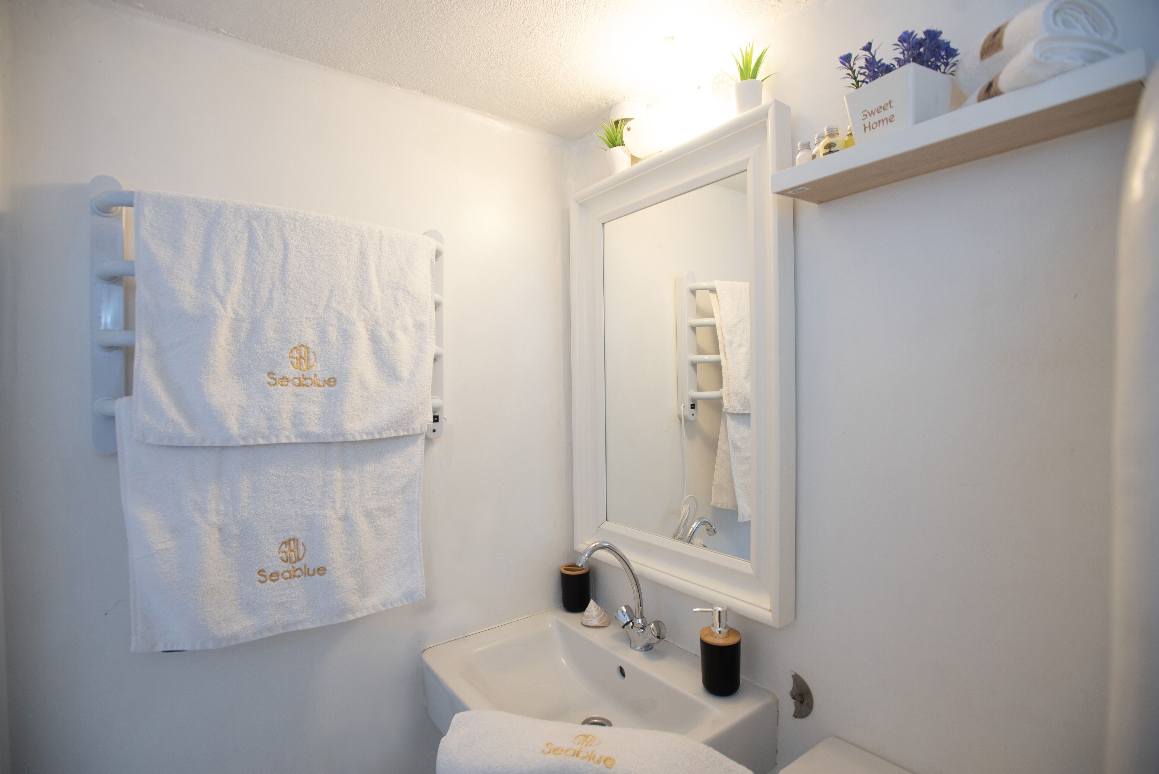 A bathroom with a white sink, a mirror, and two towels hanging on the wall, one with the logo "Seablu."