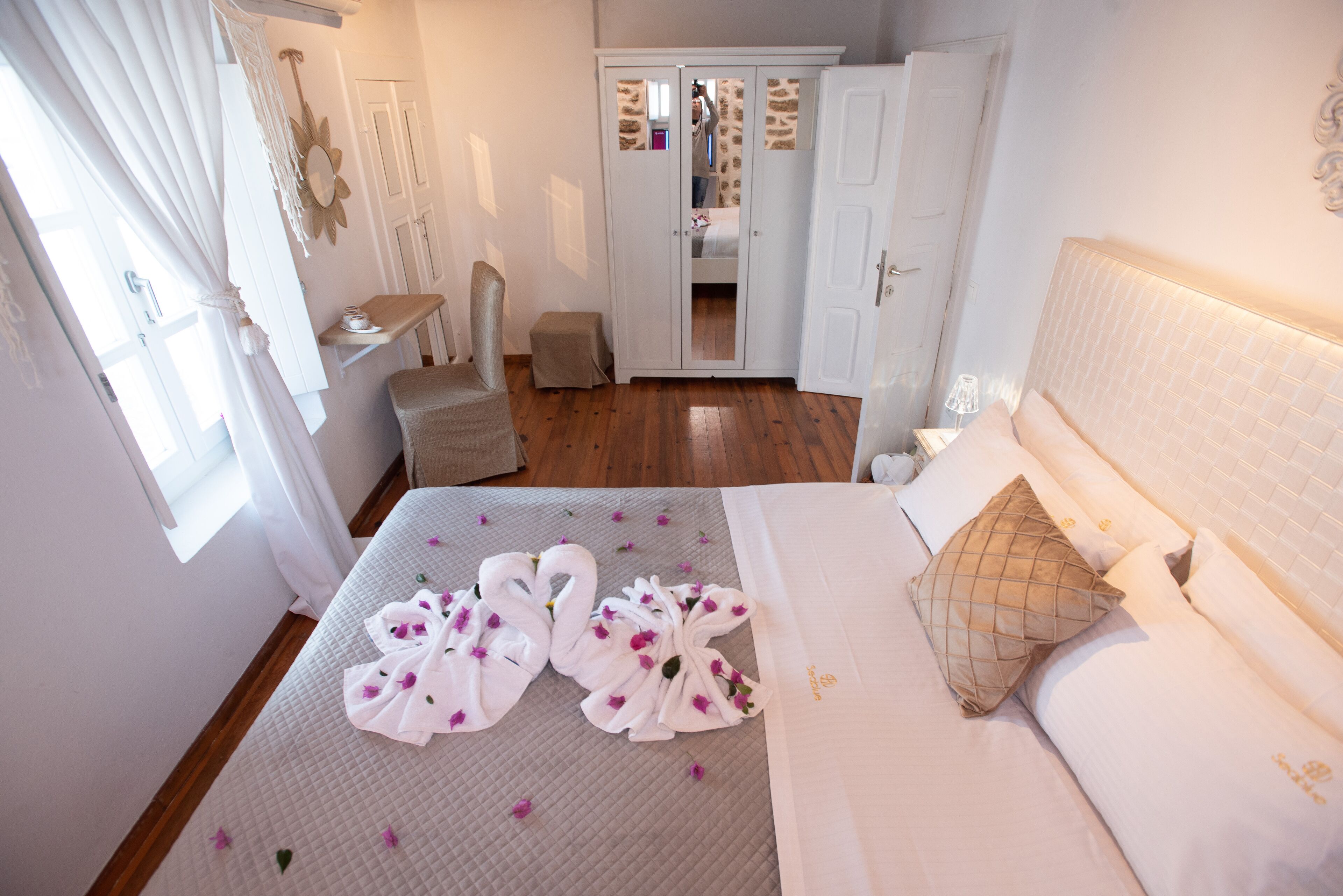 A hotel room with a bed, a chair, a desk, and a wardrobe.