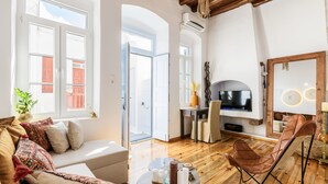 A spacious living area with a sofa, a coffee table, a TV, and a wooden floor.