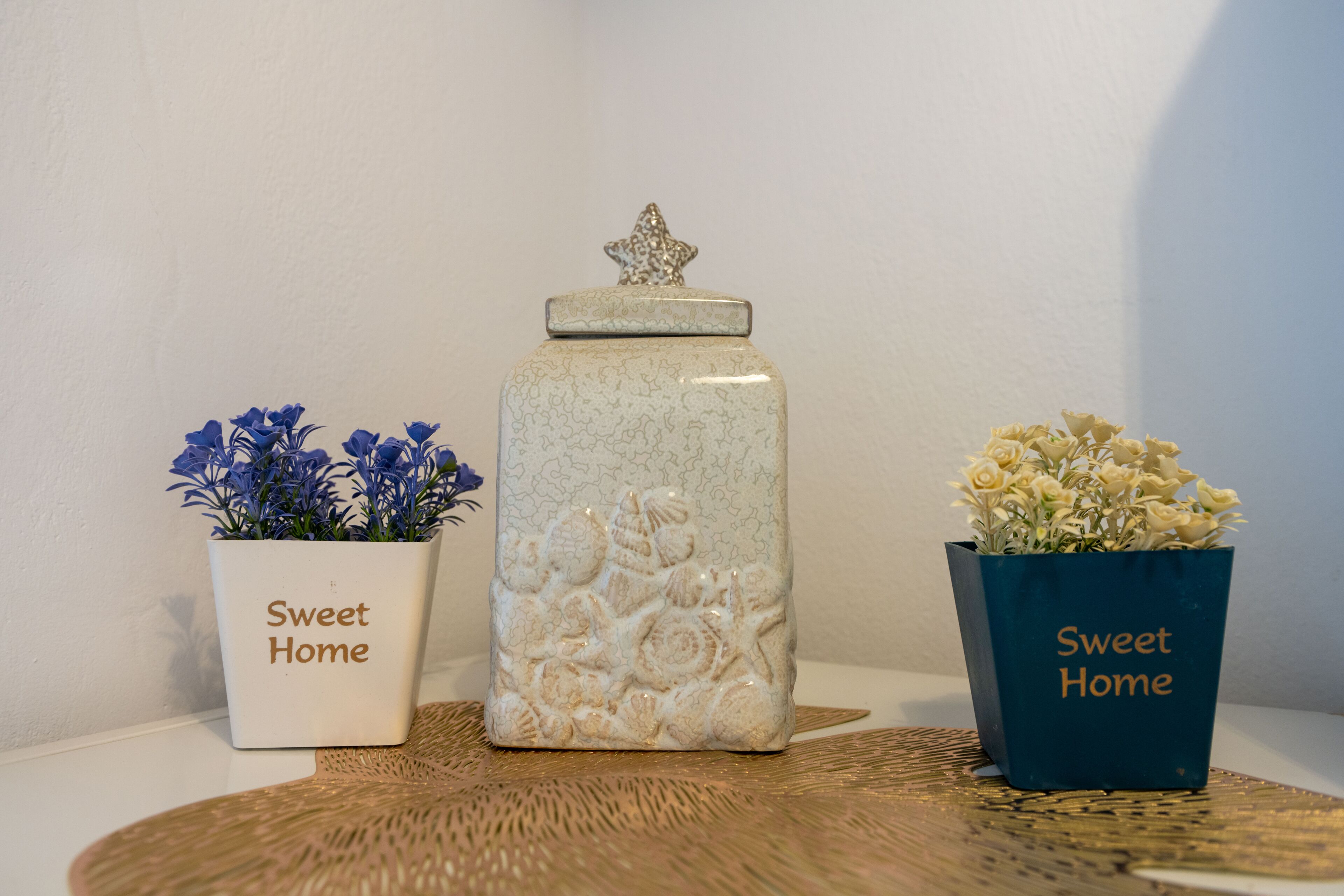 Three planters with the text "Sweet Home" on them, placed on a woven mat.
