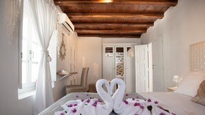 A hotel room with a bed, a wooden ceiling, a stone wall, and a door.