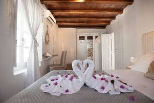 Una habitación de hotel con una cama, techo de madera, pared de piedra y una puerta.