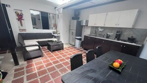 Un espace de vie compact comprenant un coin cuisine, un coin repas avec une table et des chaises, et un canapé.