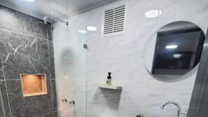 Une salle de bain moderne dotée d’une douche à parois de verre, de toilettes et d’un meuble-lavabo avec un évier.