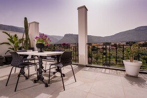A balcony with a table and chairs, potted plants, and a view of mountains. - Flat at 1 Km from the Sea in Sicily (Terrasini)