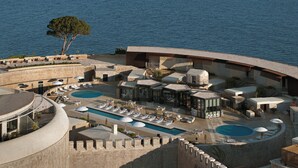 A resort with two swimming pools, outdoor seating areas, and a view of the sea. - Mamula Island by Banyan Tree (Mamula Island)