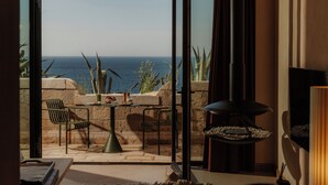 A room with a view of the sea, a table with chairs, a TV, and a fireplace. - Mamula Island by Banyan Tree (Mamula Island)
