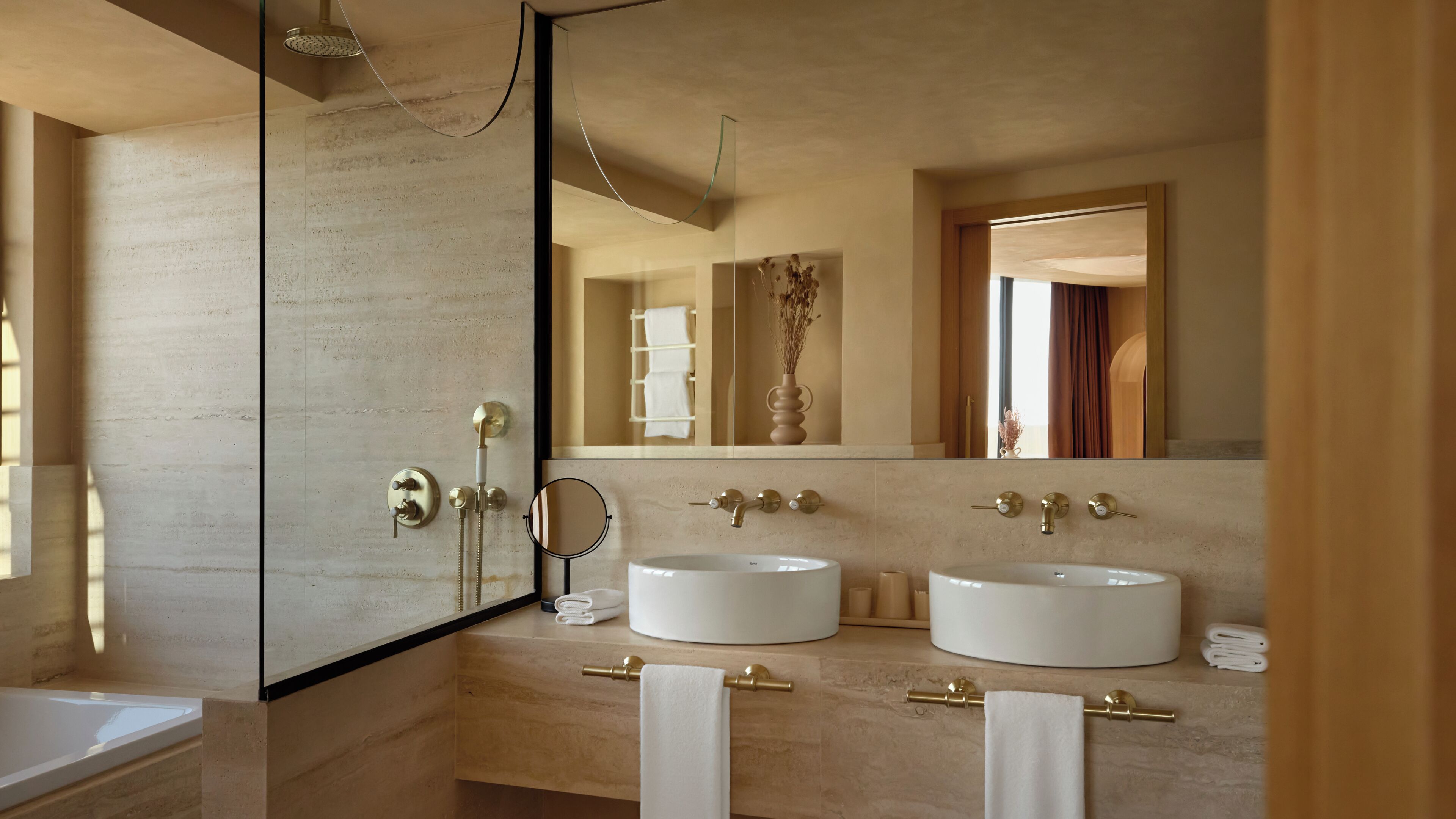 A modern bathroom with two sinks, a large mirror, and a shower.
