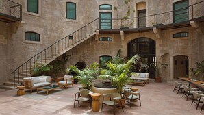 A spacious atrium with a central fountain, surrounded by seating areas and potted plants. - Mamula Island by Banyan Tree (Mamula Island)
