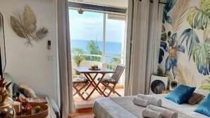 Una camera d'hotel con un letto, una scrivania, una sedia e vista mare.