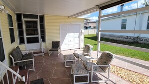 A covered patio with outdoor furniture and a view of a neighboring house.