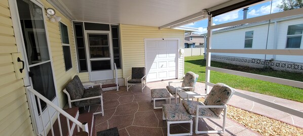 A covered patio with outdoor furniture and a view of a neighboring house. - Safe 55+ Golf community with many amenities. Close to work, shopping and dining (Lakeland)