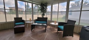 A covered patio area with wicker furniture, a glass table, and a potted plant. - Safe 55+ Golf community with many amenities. Close to work, shopping and dining (Lakeland)