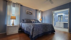 A bedroom with a bed, nightstands, a dresser, a mirror, and a window with curtains.