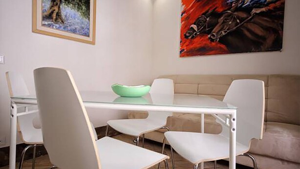 A modern dining area with a glass table, white chairs, and a beige sofa. - Fisherman's House (Trapani)