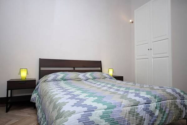 A bedroom with a bed, two bedside tables, and a wardrobe. - Fisherman's House (Trapani)