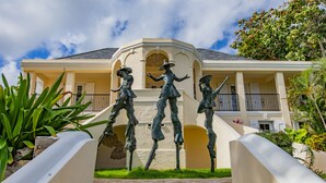 Un edificio con una escalera central que conduce a una entrada, flanqueada por estatuas.