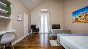 Un dormitorio con una cama, un escritorio, una silla, un televisor y un cuadro en la pared.