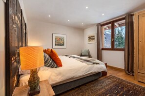 A bedroom with a bed, a lamp, a rug, and two framed pictures on the wall.
