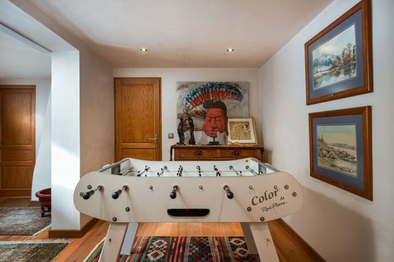 A room with a foosball table, wooden cabinets, a door, and framed artwork on the walls.