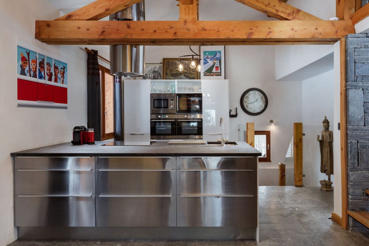 Een moderne keuken met roestvrijstalen apparatuur, houten balken en een stenen muur.