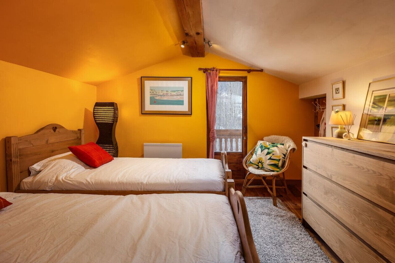 Un dormitorio con dos camas, un aparador de madera, una silla y una ventana con vistas.