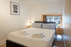 Un lit bien fait avec deux oreillers, une table de chevet avec une lampe et un tableau encadré au mur.