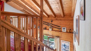 A wooden interior with exposed beams, a staircase, and a view of the outdoors.