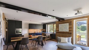 Une cuisine moderne avec des meubles de rangement de couleur sombre, une table à manger en bois et une grande fenêtre.