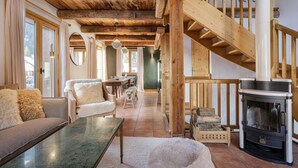 Un interior acogedor con una escalera de madera, una chimenea, un sofá y un comedor.