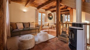 Una sala de estar acogedora con un sofá, sillones, una chimenea y un techo de madera.